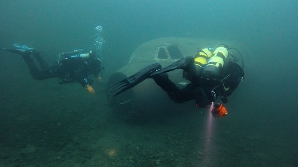divers swim towards wreck